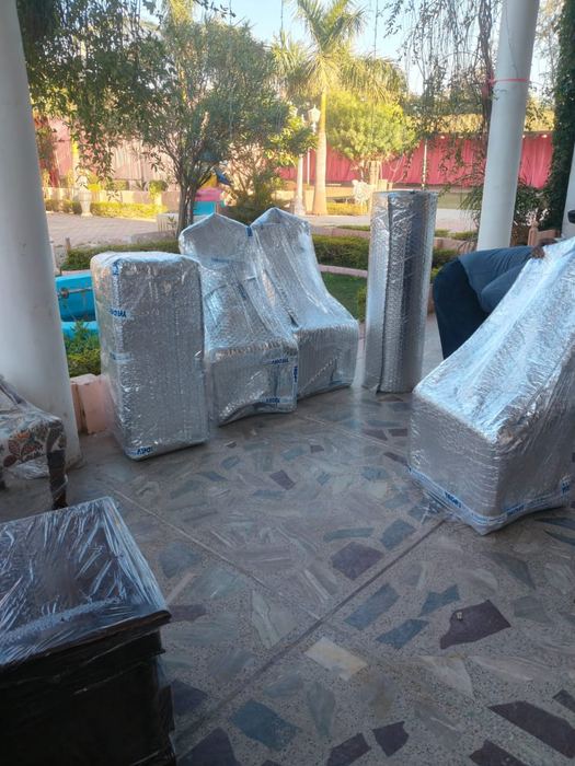 Wrapped furniture and rolled carpet packed for a house shift in Jaipur